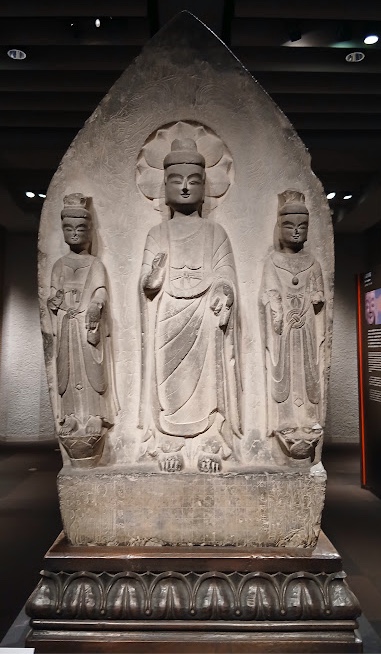 舟形の大きな光背の前に中尊と両脇侍が並ぶ、東魏時代の石灰岩の如来三尊立像