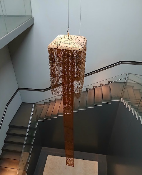 階段上の吹き抜けに垂れ下がる金銅の灌頂幡と、展示ケースに並ぶ透彫の幡身