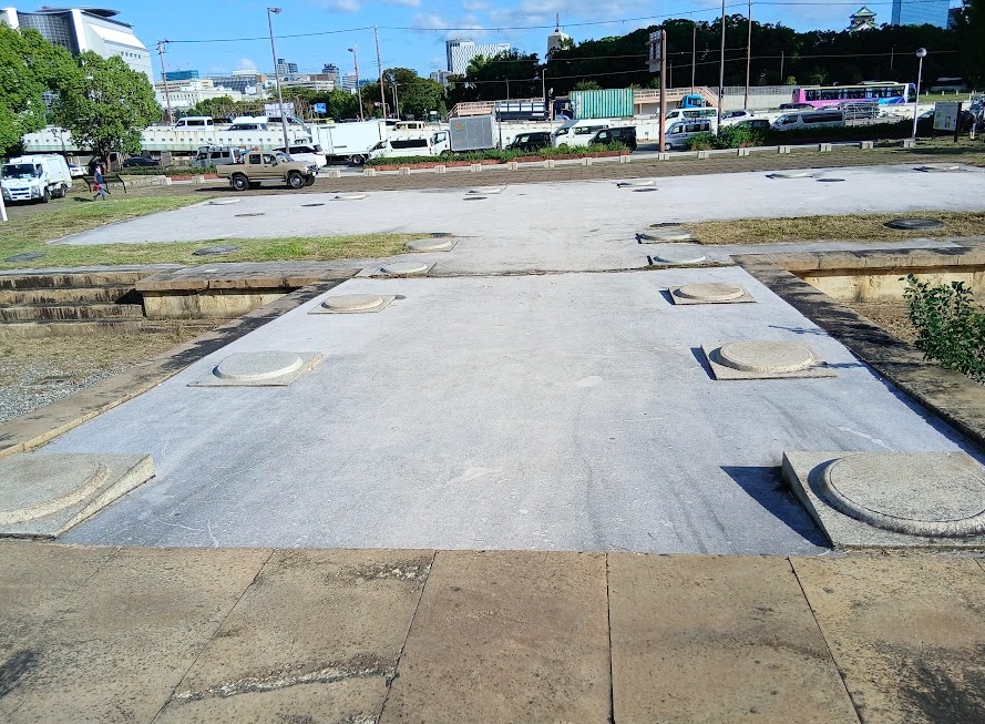 基壇の上の丸い印は、大極殿の柱が立っていた位置。奥には地面の高さを走る阪神高速が見えます